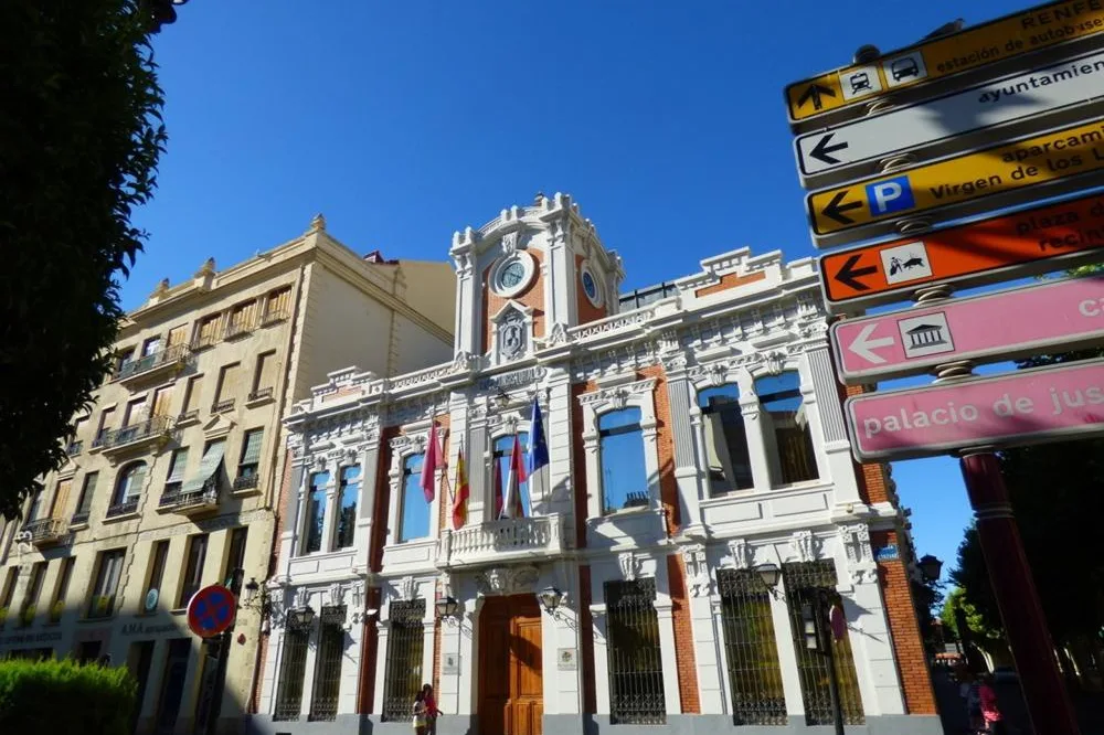 Fachada de un edificio histórico con reloj y banderas en el centro de Albacete